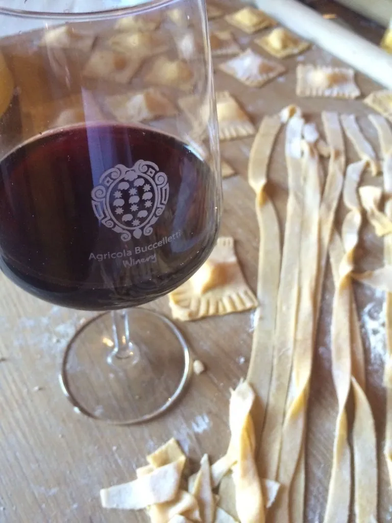 A glass of red wine next to fresh homemade pasta.