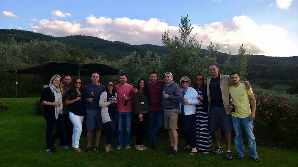 A group of people posing outdoors with mountains and sky in the background.