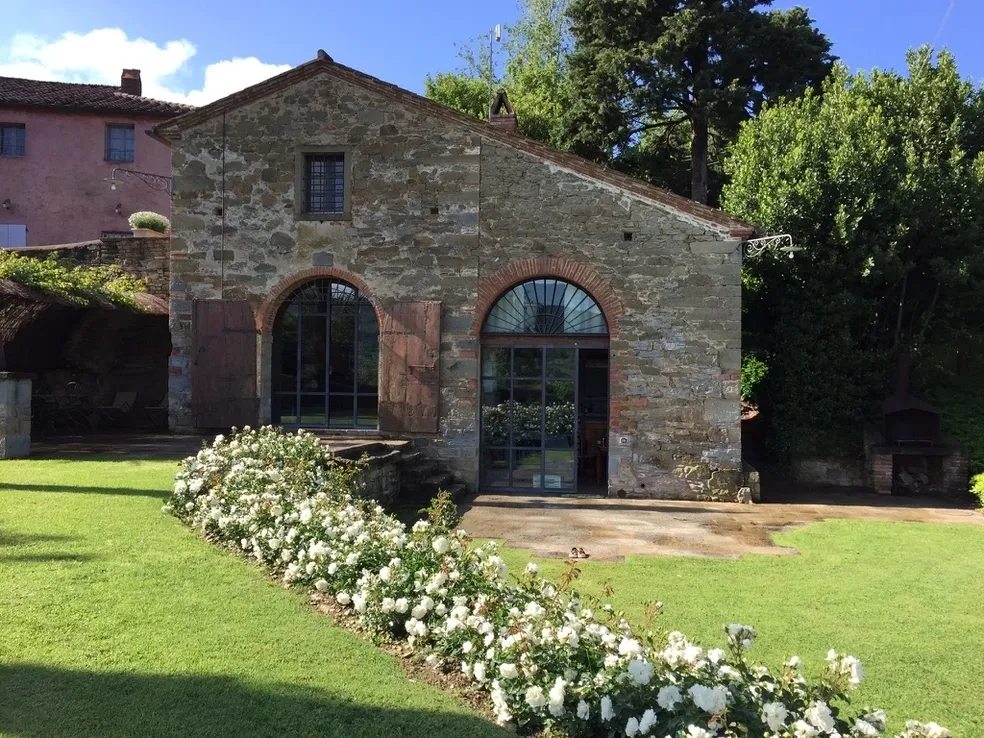 Stone building with arched windows and white flowers in front.